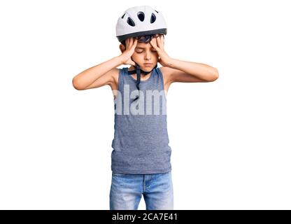 Kleine niedliche Junge Kind trägt Fahrradhelm leiden unter Kopfschmerzen verzweifelt und gestresst, weil Schmerzen und Migräne. Hände auf dem Kopf. Stockfoto