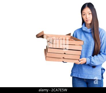 Junge schöne chinesische Frau hält Pappkartons der italienischen Pizza Denken Haltung und nüchternen Ausdruck selbstbewusst suchen Stockfoto