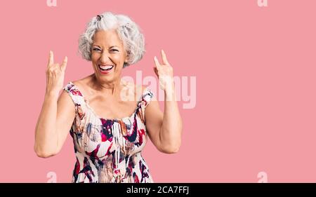 Ältere grauhaarige Frau trägt Freizeitkleidung schreien mit verrückten Ausdruck Rock-Symbol mit Händen nach oben. Musik-Star. Heavy-Konzept. Stockfoto