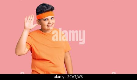 Kleiner Junge, der Sportkleidung trägt und freundlich grüßt und lächelt Stockfoto