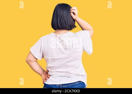 Brunette Frau mit Down-Syndrom tragen casual weißen T-Shirt rückwärts denken Zweifel mit Hand auf Kopf Stockfoto