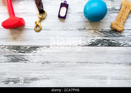 Hundezubehör mit Gegenständen wie Hantel, Leine, Klicker, Ball und Treat. Blick von oben auf Holz. Gegenstände für Clicker-Training Stockfoto