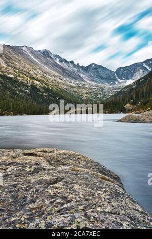 Mühlen See lange Exposition. Rocky Mountain Nationalpark See in colorado. Blaues Wasser und schneebedeckte Berge sichtbar. Kiefern, Felsen und Wasser führen Th Stockfoto