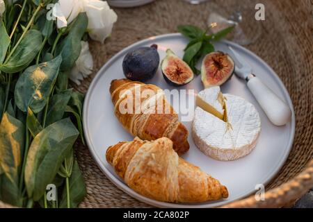 Horizontales Bild von Croissants, Feigen und Kamberkäse in einem minimalistischen weißen Teller. Stockfoto