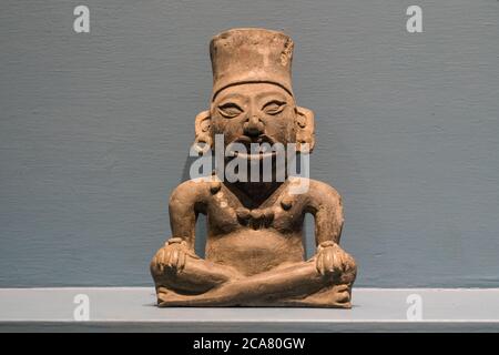 Eine Graburne in Form eines Mannes, der im Monte Alban Site Museum, Oaxaca, Mexiko, sitzt. Ein UNESCO-Weltkulturerbe. Stockfoto
