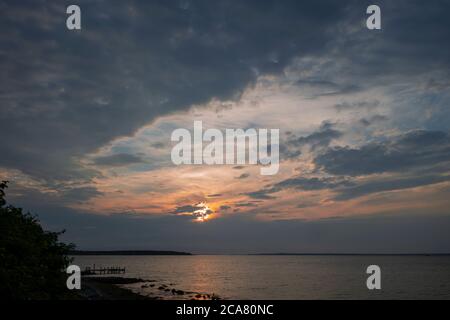 Schöner Ozeanhimmel blau gelb orange Sonnenaufgang Sonnenuntergang hinter dunklen Wolken Stockfoto