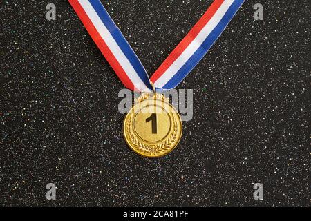 Goldmedaille 1 Platz mit Band auf schwarzem Glitzer-Hintergrund. Konzept für Sieg oder Erfolg, Award-Konzept Stockfoto