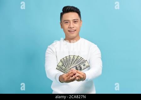 Attraktive asiatische Mann hält einen Fan von hundert Dollar Scheine über weißem Hintergrund. Stockfoto