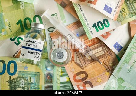 Coronavirus Covid-19 Impfstoff Preis / Kosten Konzept - Glasfläschchen mit silberner Kappe auf Haufen von Euro-Banknoten, Spritze in der Nähe, Nahaufnahme Detail (eigene Aufkleber d Stockfoto