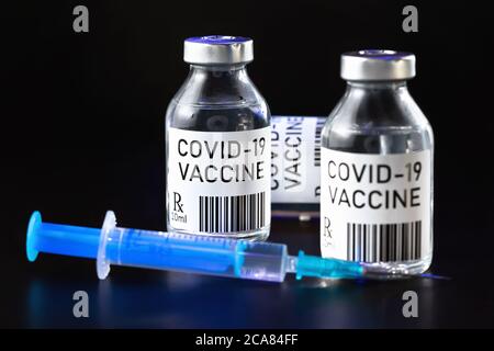 Coronavirus Covid-19 Impfstoffkonzept - drei Glasfläschchen auf schwarzem Tisch, hypodermische Spritzennadel in der Nähe, Nahaufnahme Detail (Label eigenes Design - Dummy dat Stockfoto