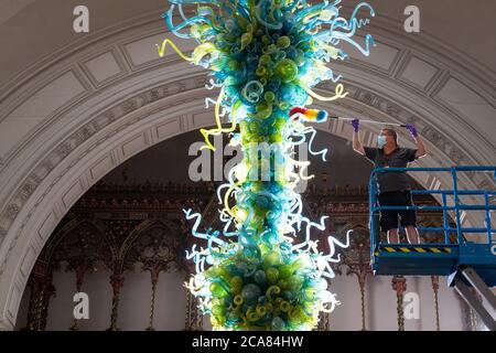 Museumstechniker Andy Monk reinigt den 27 Meter langen Rotunda-Kronleuchter von Dale Chihuly, der aus 1,300 blauen und grünen Glaselementen besteht, im Victoria and Albert Museum in London, während er sich auf die Wiedereröffnung am 6. August vorbereitet. Stockfoto