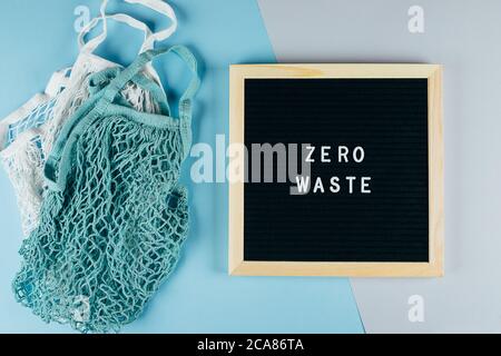 Zwei wiederverwendbare Baumwollbeutel (Netzbeutel) und Message Board mit Text Zero Waste. Umweltfreundliches Konzept. Flach liegend, Draufsicht Stockfoto
