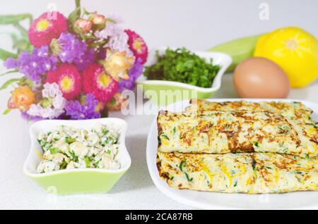 Köstliche Omelette Rolle mit Käse und Zucchini Füllung auf einem weißen Tisch Stockfoto