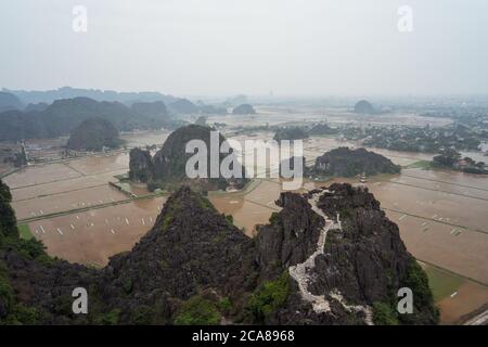 TAM Coc / Vietnam - 25. Januar 2020: Wunderschöne Landschaft mit Bergpagode bei Bich Dong mit überfluteten Reisfeldern und bewölktem Himmel Stockfoto