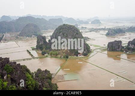 Ninh Binh / Vietnam - 25. Januar 2020: Luftaufnahme des Ninh Binh Karstgebirges mit einem Haus umgeben von überschwemmten Reisfeldern Stockfoto