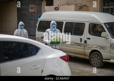 (200805) -- URUMQI, 5. August 2020 (Xinhua) -- der Freiwillige Ekebar Emet (R) hält eine Wassermelone, um sie an den Bewohner des Tianshan Bezirks Urumqi, nordwestlich der Autonomen Region Xinjiang Uygur in China, zu liefern, 3. August 2020. Ekebar Emet, eine 21-jährige junge Studentin, kommt aus dem Landkreis Bachu in Xinjiang. Am 3. Juni ging er zur Gemeinde Dongcaiyuan im Bezirk Tianshan der Stadt Urumqi, um dort ein Jahr lang zu praktizieren. Das plötzliche Wiederaufleben von COVID-19 in Xinjiang verwandelte Ekebar sofort von einem Universitätspraktikanten zu einem Freiwilligen an der Front der Epidemien-Prävention und -Kontrolle. Ekebar veröffentlichte epi Stockfoto