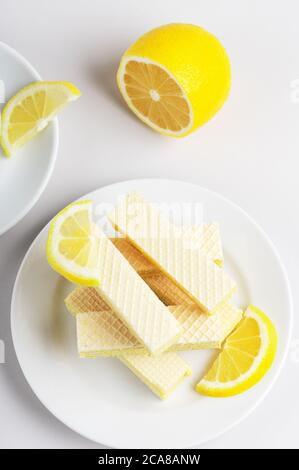 Blick von oben auf süße und leckere Dessert und die Hälfte der Limette. Waffeln mit Milchfüllung. Wafer aufeinander auf Platte auf weißem Hintergrund. Teezeit. Scheiben o Stockfoto