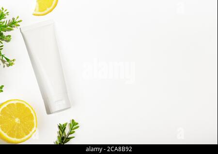 Draufsicht auf weiße ungebrandete Tube mit grüner Pflanze und saftiger Zitrone. Blank Flakon für Naturkosmetikprodukte. Behälter für nahrhafte Creme, Körper sc Stockfoto