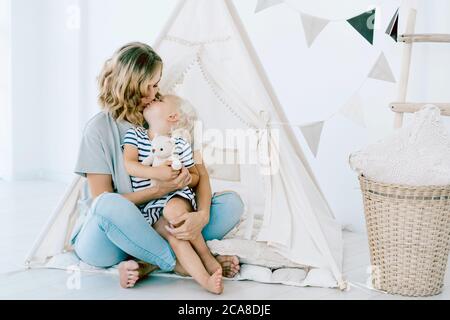 Mama umarmt ihre kleine charmante Tochter und küsst sie. Stockfoto