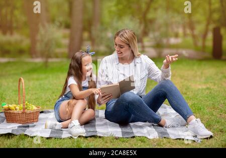 Positive Mutter Und Tochter Lesen Und Diskutieren Buch Im Park Stockfoto