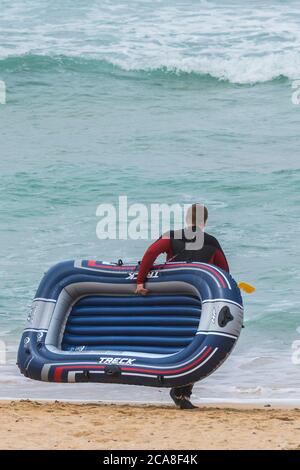 Ein Urlauber mit einem Schlauchboot auf Fistral; Beach in Newquay in Cornwall. Stockfoto