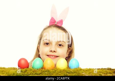 Kleines Mädchen oder süßes Kind mit fröhlichem Gesicht und pinkfarbenen Hasenohren auf blondem Kopf, das mit bunten ostereiern aufposiert, die auf weißem Hintergrund isoliert sind Stockfoto