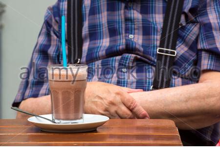 Ein Glas heißer Schokolade vor einem eldlerischen Mann in Bayern, Deutschland Stockfoto