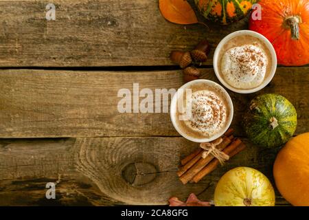 Kürbis gewürzter Latte in orangefarbenen Gläsern auf Holzhintergrund Stockfoto