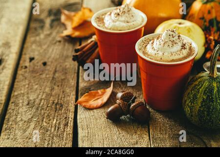 Kürbis gewürzter Latte in orangefarbenen Gläsern auf Holzhintergrund Stockfoto