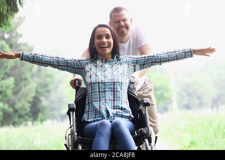 Eine junge Frau sitzt auf einem Rollstuhl im Wald Stockfoto