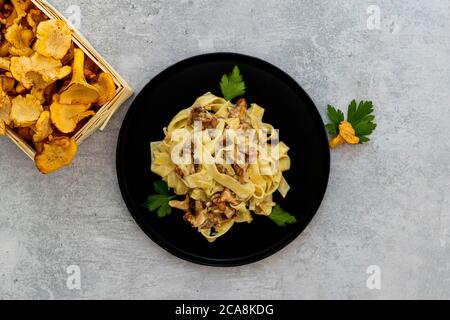 Italienische Pasta Tagliatelle mit Pfifferlingen und Petersilie auf einem schwarzen Teller Stockfoto