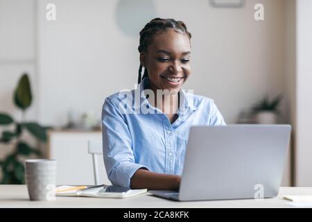 Young Black Secretary Arbeitet Am Laptop In Modernen Büro, Tippen Auf Der Tastatur Stockfoto