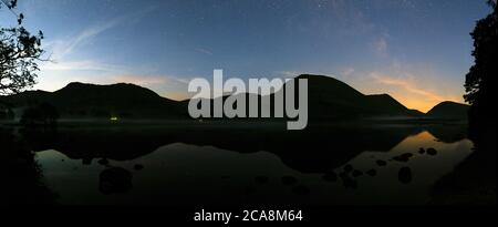 Eine Panoramaaussicht auf Brotherswater mit einem Nebel auf dem Wasser und einer schwachen Milchstraße. Stockfoto