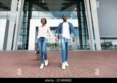 Bereit Für Abenteuer. Aufgeregt Schwarzes Paar Verlassen Airport Building In New Country Stockfoto