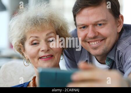 Erwachsener Sohn zeigt Mutter ein Foto im Telefon Stockfoto