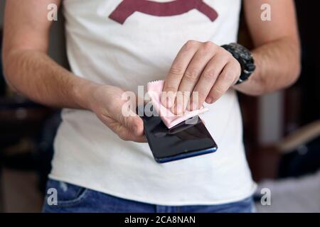 Desinfektion des Telefons. Entfernen von Keimen und Viren von Ihrem mobilen Gerät. Männliche Hände wischen Staub Touchscreen Handy Stockfoto