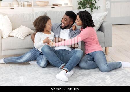 Zeitvertreib Für Die Ganze Familie. Happy Black Eltern Spielen Mit Ihrer Kleinen Tochter Zu Hause Stockfoto