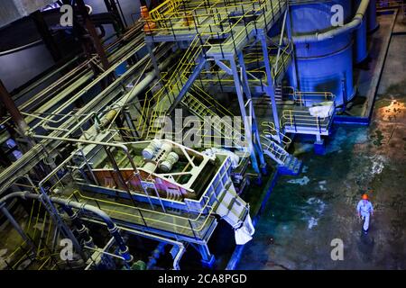 Akbakay/Kasachstan - April 23 2012: Pumpstation der Goldbergbau- und Verarbeitungsanlage mit Arbeiter in blauem Schutzanzug und orangefarbenem Helm. Altynalmas Stockfoto