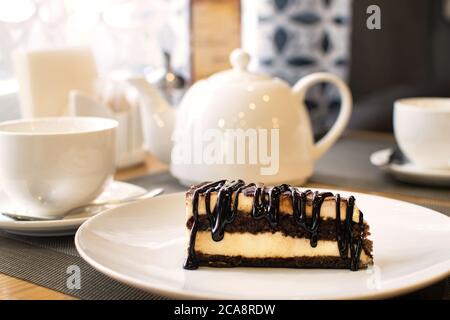 Scheibe von leckeren Tiramisu auf weißem Teller auf dem Tisch im Café. Traditionelle italienische Biskuit Dessert oder Kuchen. Stockfoto