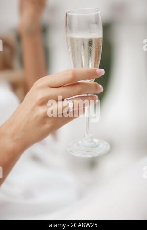 Hochzeit und Engagement Ring auf der Hand mit Champagner. Frau Hand mit einem Glas Sekt Stockfoto