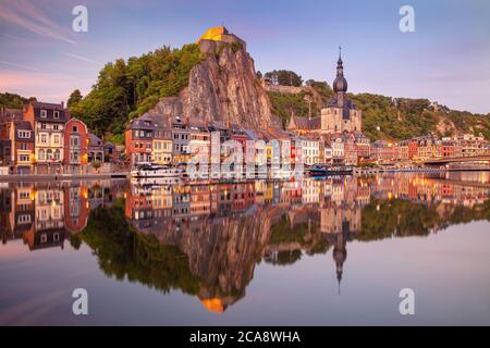 Dinant, Belgien. Stadtbild Bild der schönen historischen Stadt Dinant mit der Reflexion der Stadt in der Maas Fluss bei Sommeruntergang. Stockfoto