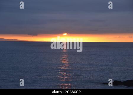 Sonnenuntergang über Tapia de Casariego, in Asturien. Wir können sehen, wie die Sonne fällt und sich am Meer versteckt, bis sie verschwindet. Stockfoto