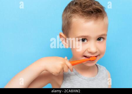 Netter kleiner Junge, der mit einer Handzahnbürste Zähne putzt. Kopfschuss auf blauem Hintergrund Stockfoto