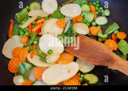 Gefrorenes Gemüse aus der Verpackung wird in einer Pfanne gebraten. Gemüse der schnellen Zubereitung aus dem Gefrierschrank werden gebraten. Fast Food, Snacks, gesunde f Stockfoto