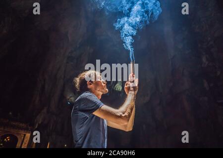 Junger Mann, der in einem buddhistischen Tempel betet und Weihrauch hält Huyen Khong Höhle mit Schreinen, Marmorberge, Vietnam Stockfoto