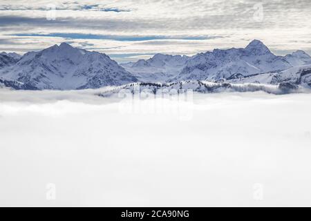 Schneebedeckte Berge mit Inversion Valley Nebel und Bäume in Nebel gehüllt. Malerische verschneite Winterlandschaft in Alpen, Allgau, Kleinwalsertal, Bayern Stockfoto