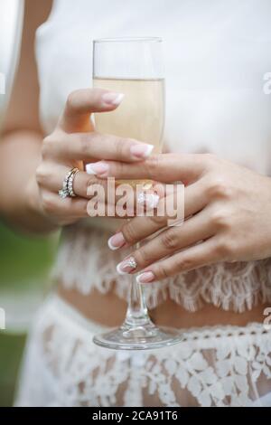 Hochzeit und Engagement Ring auf der Hand mit Champagner. Frau Hand mit einem Glas Sekt Stockfoto