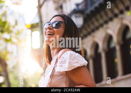 Frau mit Sonnenbrille lächelt, als sie durch die Stadt geht Stockfoto