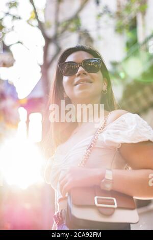 Frau mit Sonnenbrille lächelt, als sie durch die Stadt geht Stockfoto