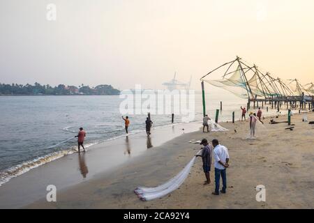 Fischer am Strand vor chinesischen Fischernetzen, Fort Kochi, Cochin (Kochi), Kerala, Indien, Asien Stockfoto